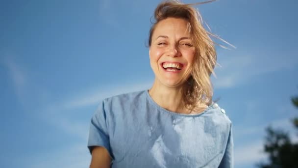 Jolie fille heureuse dans une robe en denim. Portrait ensoleillé d'une jeune femme avec un sourire aux dents blanches contre le ciel — Video