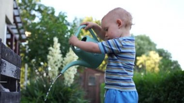 Bahçe bahçesinde çiçekleri sulayan tatlı sarışın bebek. Suyla oynayan mutlu bir çocukluk dönemi. Çocuk su döker ve gider.