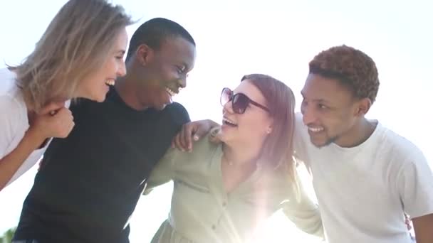 Retrato cercano de cuatro estudiantes interracial abrazando y riendo, retrato soleado. Gente feliz. Igualdad y fraternidad. Las vidas negras importan — Vídeo de stock