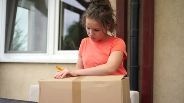 Gadis kecil membuka paket pos besar. Pengiriman tanpa kontak, pengiriman kurir, belanja online. Makanan dan barang-barang yang tidak menular selama karantina coronavirus bagi orang-orang yang terisolasi. — Stok Video