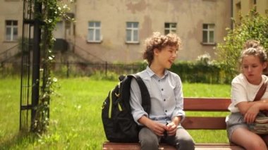 Okul çocukları, bir oğlan ve iki kız okul bahçesindeki bankta oturmuş konuşuyorlar. Okul tatili, mutlu çocukluk, sınıf arkadaşları iletişim kuruyor. Okula geri dön.