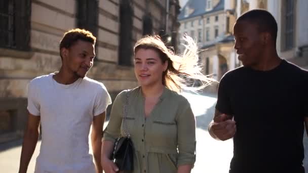 Interrassische Studentengruppe. Weißes Mädchen in Gesellschaft zweier schwarzer Jungs durch die Straßen der Stadt — Stockvideo