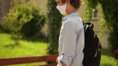 Maskeli öğrenciler Coronavirus covid-19 karantinası sırasında güvenlik kurallarına uyarlar. Çocuklar ellerini dezenfekte eder ve temassız selamlarlar. Temassız selamlama