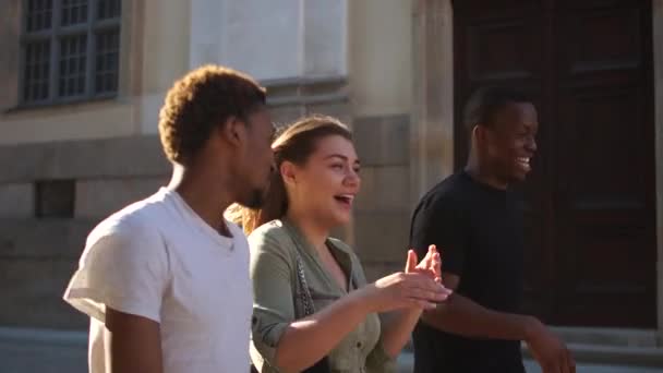 Grupo de estudantes multi étnicos andando em uma cidade. Dois afro-americanos e uma caucasiana estão a desfrutar de uma caminhada. Estudantes em uma caminhada, grupo interracial de jovens — Vídeo de Stock