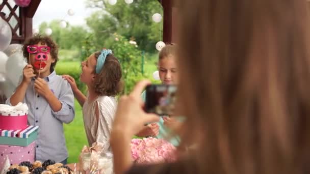 Crianças em idade escolar inteligentes são fotografadas em uma festa de aniversário de amigos. infância feliz, organização de eventos, agência de catering — Vídeo de Stock