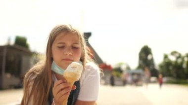 Coronavirus covid-19 sırasındaki iki kızın güneşli şehir portresi. İki genç kız maskelerini çıkardı ve dondurma yiyorlar.