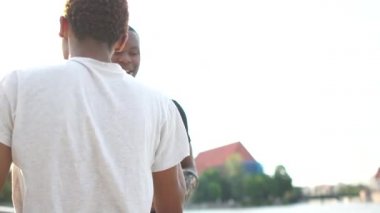 İki dost canlısı genç adamın yakından çekilmiş portresi, Afrikalı Amerikalı öğrenciler gülüyor ve konuşarak eğleniyorlar. Açık şehir portresi. İki siyah adam, iki arkadaş.