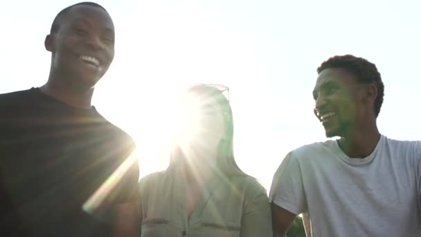 Międzyrasowa grupa studentów na spacer po mieście. Biała kobieta i dwóch czarnych mężczyzn bawi się podczas spaceru o zachodzie słońca. Portret odblaskowy słońca — Wideo stockowe