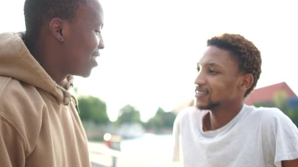 Міський портрет двох афроамериканських хлопців, які розмовляють і посміхаються один до одного. Гомосексуальна пара — стокове відео