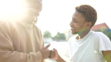 İki siyah arkadaş, iki Afrikalı Amerikalı öğrenci birbirlerini yumruklarıyla selamlıyorlar. Açık hava portresini kapat