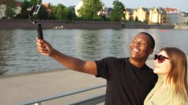 Çok ırklı bir grup insan. Üç sevimli öğrenci arkadaş, bir Avrupa şehrinin köprüsünde akıllı telefon ve selfie çubuğu kullanarak fotoğraf çekiyorlar. Seyahat ve dostluk içeriği