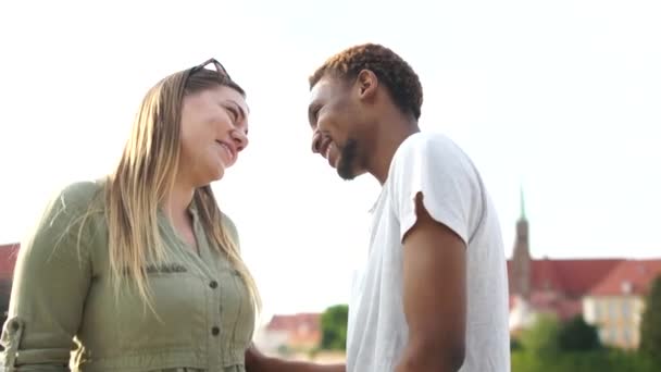 Man and woman, interracial couple flirts while standing opposite each other on the bridge. Lovers date, black man and white woman, students couple in love — Stock Video