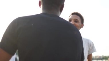 İki arkadaş canlısı gencin yakın portresi, mutlu öğrenciler. İki Afrikalı Amerikalı öğrencinin buluşması, hoş geldiniz tokalaşması ve kucaklaşması.