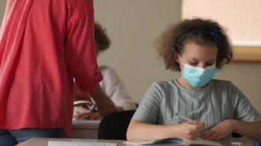 Okula dönelim. Sınıfın önünde duran öğretmen yeni bir konuyu açıklıyor. Maskeli çocuklar dikkatle dinliyorlar ve yazıyorlar. Yeni normallik, okulları yeniden açmak