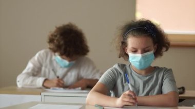Okulları yeniden açmak. Maskeli okullu çocuklar. Okuluna geri dön. Oğlan kıza notu iletir.