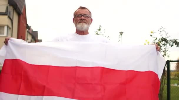 Beyaz Rusya 'da protesto. Bir adam Belarus 'un bayrağını tutar ve kollarıyla gökyüzünün ve güneşin arka planına doğru uzatır. — Stok video