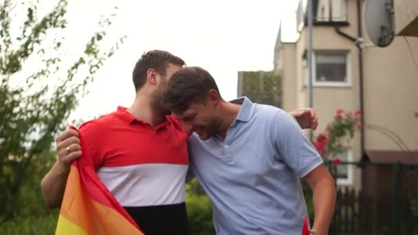 Feliz casal gay abraçando e mostrando seu amor com bandeira do arco-íris. LGBT e conceito de amor — Vídeo de Stock