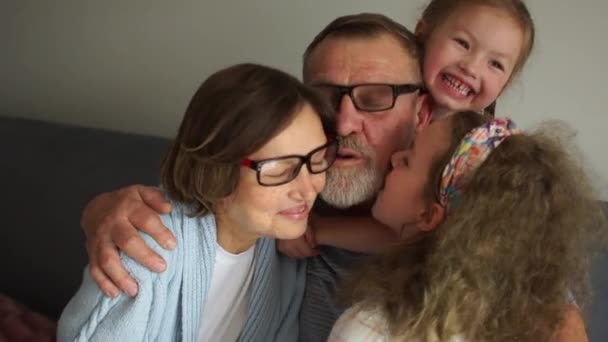 Glada morföräldrar och två barnbarn. Stäng Inomhus porträtt. Morfar och mormor skrattar och ha kul med två små barnbarn — Stockvideo