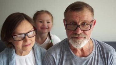 Torunuyla birlikte mutlu bir son sınıf çifti portresi. Büyükanneleriyle büyükbabalarının kanepede oturan küçük torunlarının portresi. Büyük anne ve büyük baba ve torun eğleniyor, mutlu aile.