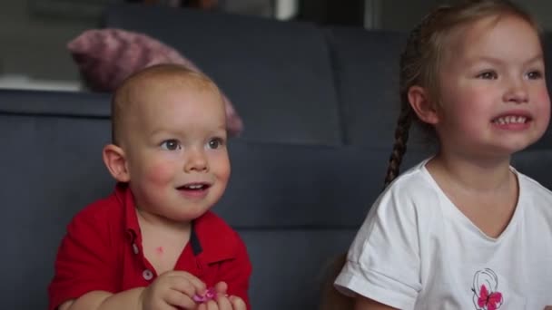 Mooie kleine jongen en meisje klappen in hun handen en glimlachen. Twee kleine kinderen, een jongen en een meisje, klappen in hun handen en hebben plezier samen. Indoor portret, happy childhood concept — Stockvideo