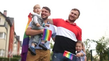 Eşcinsel çift. Evlerinin yanında bayrakları, iki çocuğu, bir oğlu ve bir kızı olan mutlu bir eşcinsel aile. Gay hakları, Igbt topluluğu, çocuk evlat edinme, babalar günü.