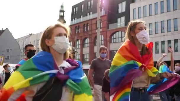 Wroclaw, Polen - 3 oktober 2020. Jämställdhetsmarsch för Polen. Två unga flickor i masker med hbt-flaggor på axlarna går i folkmassan och dansar — Stockvideo