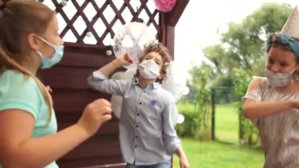 Drei Teenager tanzen maskiert zu einer Geburtstagsparty. Soziale Distanzierung, Vorsichtsmaßnahmen während der Covid-19-Coronavirus-Pandemie — Stockvideo