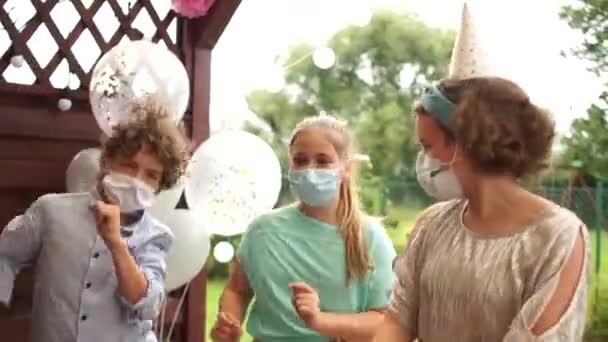 Le garçon d'anniversaire et ses deux amis à la fête dansent. Les adolescents portent des masques chirurgicaux protecteurs pendant la pandémie de coronavirus — Video