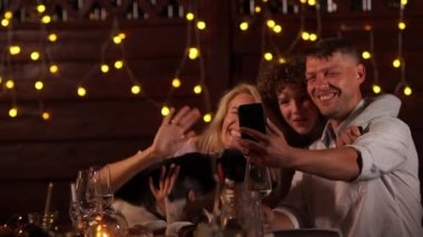 Mutlu aile, baba, anne, oğul ve köpek Noel 'i arka plandaki ışıkların karşısında kutluyor. Akıllı telefon kullanarak video görüşmesi, sosyal mesafe, video tebrikleri.