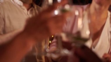 Dört yetişkin Noel masasında şenlik ışıklarının arka planında kadeh kaldırıyor. Evlilik yıldönümü. Evli çift kadeh kaldırır ve öpüşür.