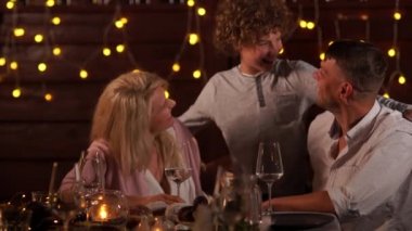 Mutlu aile Noel arifesini arka plandaki masada kutlar. Kıvırcık Çocuk Masadan Bir Kek Aldı