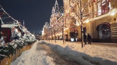 Güzel Kızıl Meydan Yeni Yıl kış süslemeleri, Moskova'nın merkezinde gece parlayan yaya sokak boyunca çekilen sabit kamera, parlak ışıklar ve topları ile ağaçlar karla kaplıdır.