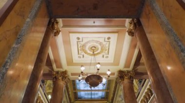 Monte Carlo, Monako - Temmuz 2018: Monte Carlo Casino'dan zengin bir şekilde dekore edilmiş tavan ve duvarlara, salonda duran ve etrafı izleyen bir adam.