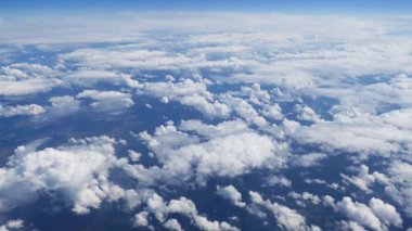 Derin mavi gökyüzünde pitoresk beyaz bulutlar üzerinde uçan. Uçak penceresinden güzel hareket eden bulutlar görünümü. Berrak mavi bulutların arasından seyahat etmek.