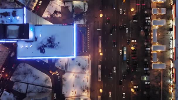 複数階建ての家々や広い通りの屋根の上を飛ぶ ニューアルバートの通りに集中的なトラフィック 高層ビルの頂上にネオンライト 夜の都会生活のトップダウンビュー — ストック動画