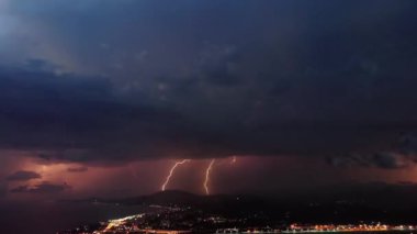 Pembe ve turuncu renklerle gökyüzünü aydınlatan pitoresk şimşek ile güzel fırtınatimelapse. Gece kıyı kenti üzerinde fırtınalı gökyüzünde birçok dramatik yıldırım yanıp söner.