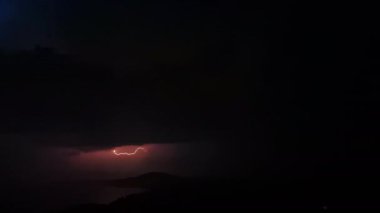 Pembe ve turuncu renklerle gökyüzünü aydınlatan pitoresk şimşek ile güzel fırtınatimelapse. Gece kıyı kenti üzerinde fırtınalı gökyüzünde birçok dramatik yıldırım yanıp söner.