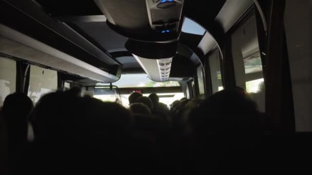 暗闇の中で人々でいっぱいの現代バスの中の後ろの列からの眺め バスはスローモーションでトンネルを移動し 明るい日光と美しい緑の風景にそれから抜け出します — ストック動画