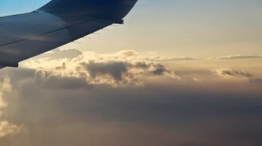 Geç güneşle birlikte akşam bulutlarının üzerinde uçuyor. Güzel güneş ışınları ile hareketli bulutların arasından uçuş. Uçak penceresinden hava yoluyla seyahat etmek. Sinema, arka plan için mükemmel