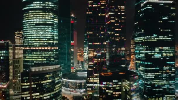 夜にモスクワ市ビジネスセンターへの上からの素晴らしいクローズアップビュー カメラはゆっくりと右から左に高層ビルの周りを移動し その明るい輝く光と現代の美しさを示しています — ストック動画