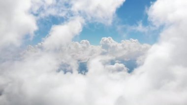 İnanılmaz güzel bulutlar arasında uçuyor. Beyaz pofuduk bulutların, açık mavi gökyüzünde usulca hareket ettiği resimli bir zaman dilimi. Kokpitten doğrudan görüntü.