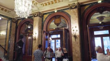 Monte Carlo, Monako - Temmuz 2018: Monte Carlo Casino görünümü içeriden. Yavaş çekimde kumarhaneye girip çıkan insanlar, salondaki şans tanrıçası heykelinin yanından geçerek.