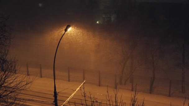 冷ややかな夜の街灯の薄暗い光の中で雪が激しく降る 寒いロシアの冬のさびれた通りに強風と吹雪 — ストック動画