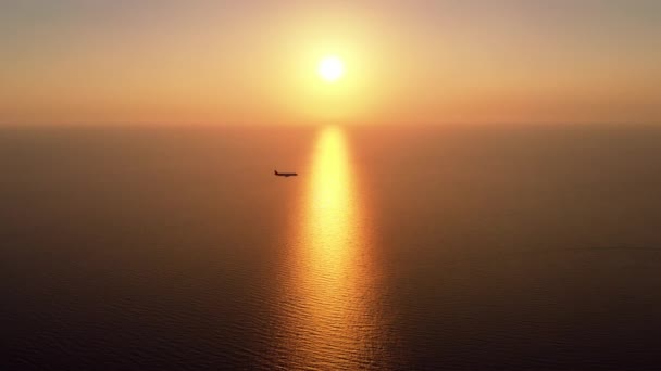 夕日の海と飛行機が飛んで素晴らしい空中パノラマ 海の上を下る太陽を眺め 水の上に光の道を残し 太陽の前の海景を横切る飛行機 — ストック動画