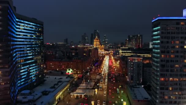 鳥の目のビューから夜のモスクワの明るい光 市内中心部のニューアルバート通りで集中的なトラフィック 広い大通りの側面にネオンライトで照らされた複数階建ての家 — ストック動画