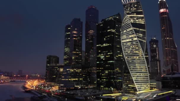 凍った川モスクワの上に照らされた窓とバゲーションブリッジを備えたモスクワ市のビジネスタワーの夜の空中ショット — ストック動画