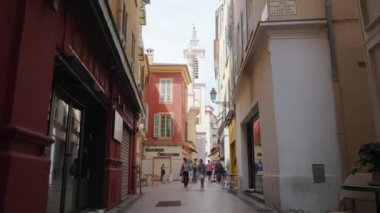 Nice, Fransa - Temmuz 2018: Avrupa'nın dar ve güzel caddesinde vitrinler, renkli binalar ve yavaş çekimde yürüyen insanlarla ilerleyen kamera.