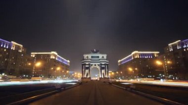 Gece yoğun bir Moskova bulvarının hareket süresi. Kamera bulvar boyunca hareket ve yürüyüş yolunun her iki tarafında trafik ve ışıltılı şehir ışıkları bir sürü ile Triumphal Kapısı geçen.