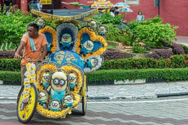 Malacca, Melaka, Malezya 15 Aralık 2017 onun renkli yumuşak oyuncaklar ile binmek müşteriler için bekleyen adam dekore edilmiş döngüsü çekçek içinde Malacca, Malaysia.