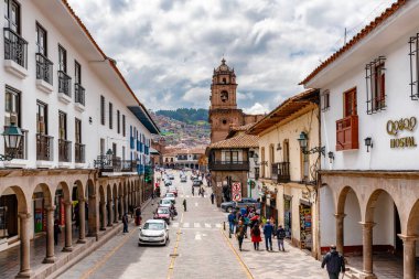 Cusco, Peru - 3 Nisan 2019: Cusco, Peru 'da arka planda bir kilise bulunan eski koloni binaları ve Plaza de Armas ile caddedeki trafiğe bakın.